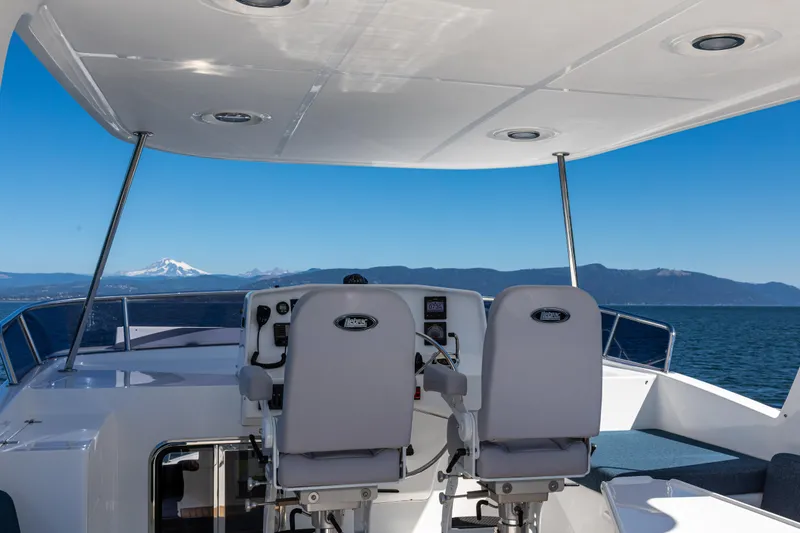 Slide: The Image of 2025 North Pacific 49 Pilothouse helm with ocean and mountain view. - 15