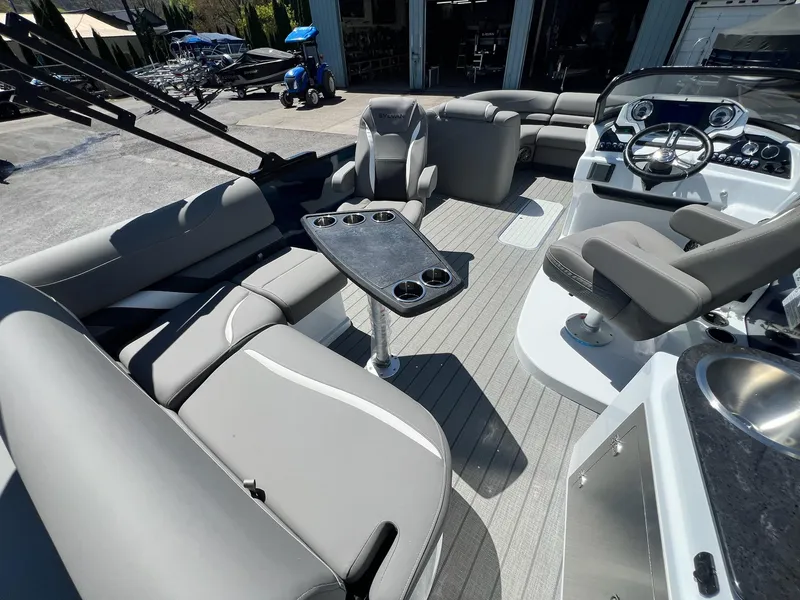 Slide: The Image of 2024 Sylvan S3 CLZ DH Tritoon interior with gray seating, steering console, and cupholder table. - 9
