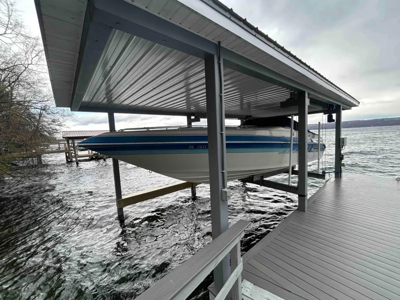 Slide: The Image of 1987 Sea Ray Pachanga 32 boat docked under a covered pier on a lake. - 0