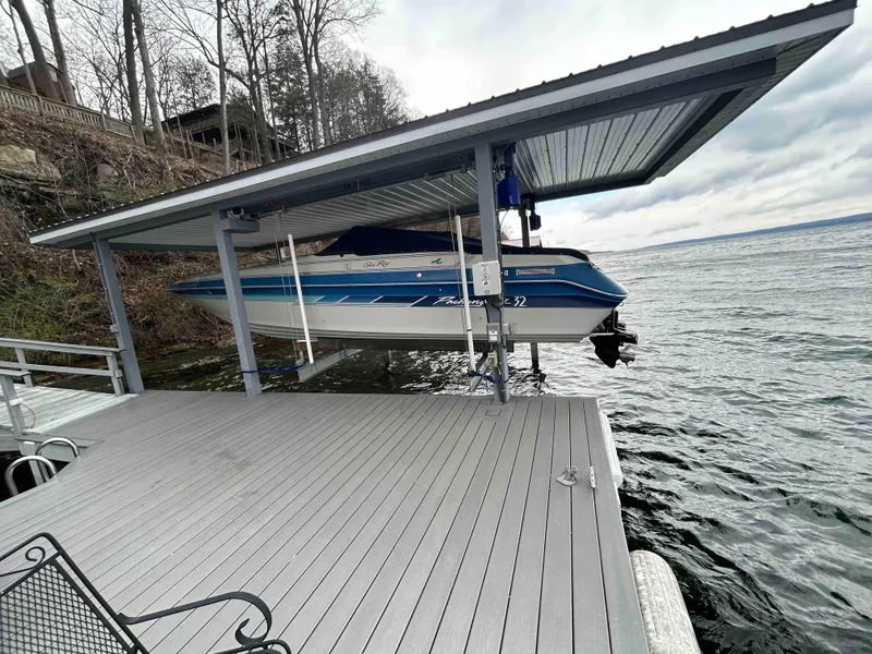 Slide: The Image of 1987 Sea Ray Pachanga 32 boat docked under a covered pier on a lake. - 1