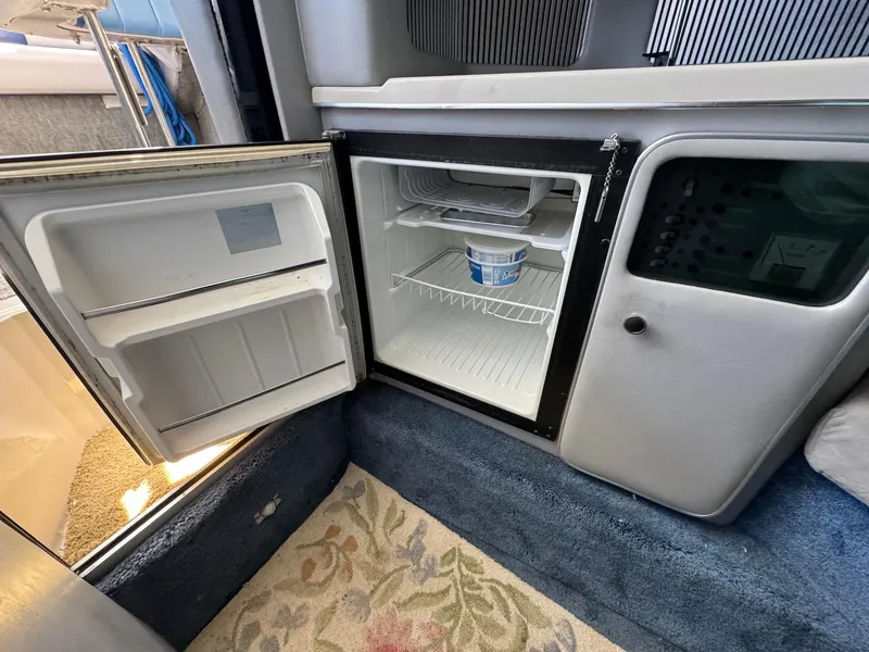 Slide: The Image of 1987 Sea Ray Pachanga 32 interior with open mini fridge and control panel. - 14
