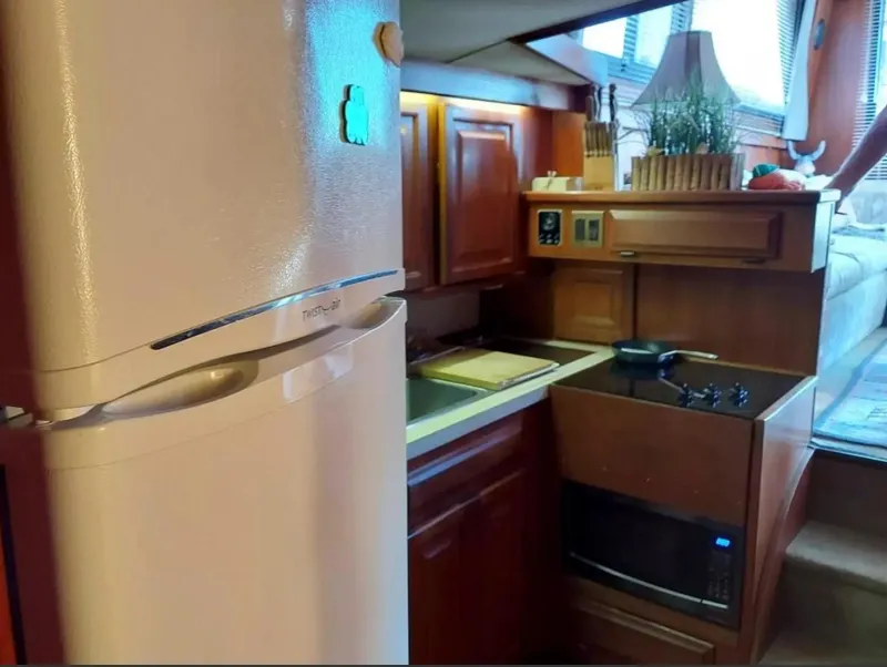 Slide: The Image of 1988 Viking 41 Convertible yacht kitchen with fridge, stove, microwave, and wooden cabinetry. - 11
