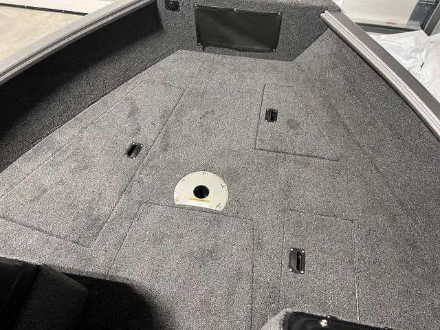 Slide: The Image of 2024 Lund 1775 Impact XS Sport boat interior with carpeted deck and storage compartments. - 27