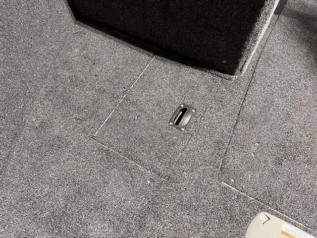 Slide: The Image of 2024 Lund 1775 Impact XS Sport boat interior with carpeted flooring and storage compartment. - 29