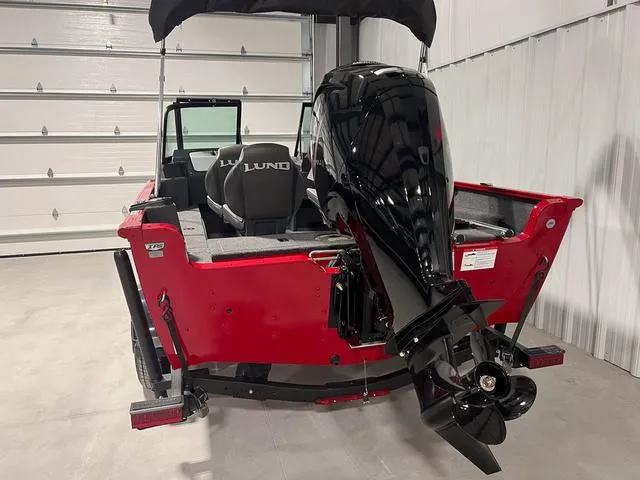 Slide: The Image of 2024 Lund 1650 Rebel XL Sport boat in a garage, rear view with outboard motor. - 4