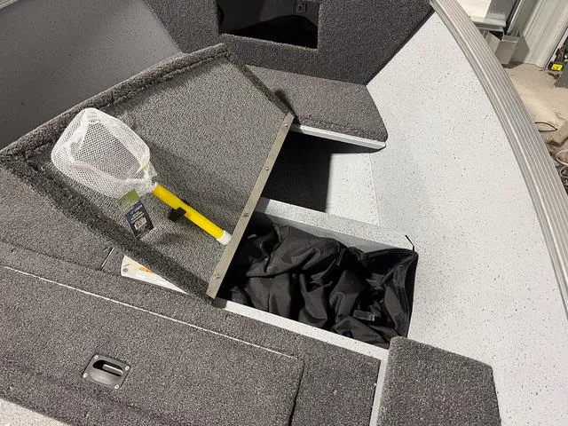 Slide: The Image of 2024 Lund 1600 Fury Tiller boat interior with storage compartment and fishing net. - 16