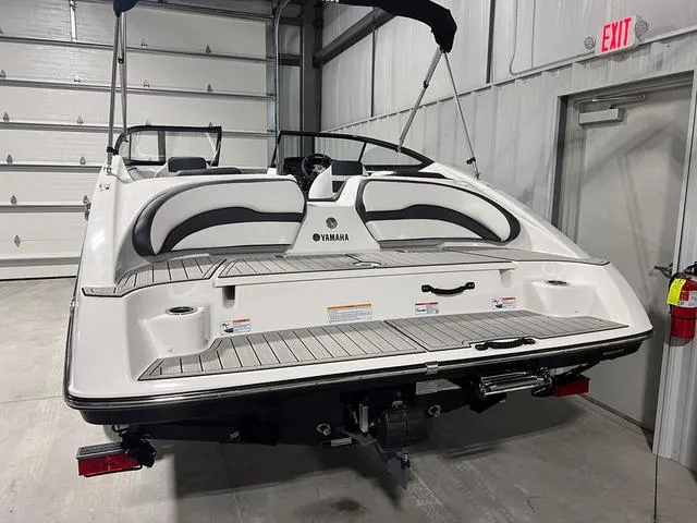 Slide: The Image of 2024 Yamaha Boats SX195 in a garage, rear view showing swim platform and seating. - 5