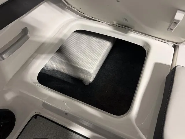 Slide: The Image of 2024 Yamaha Boats SX195 storage compartment with bubble-wrapped item. - 9