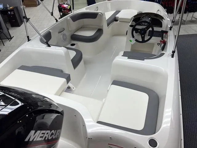 Slide: The Image of 2024 Bayliner E16 LTD boat interior with Mercury engine, white and gray seating. - 7