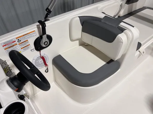 Slide: The Image of 2024 Bayliner E18 LTD boat interior with steering wheel and cushioned seating. - 17