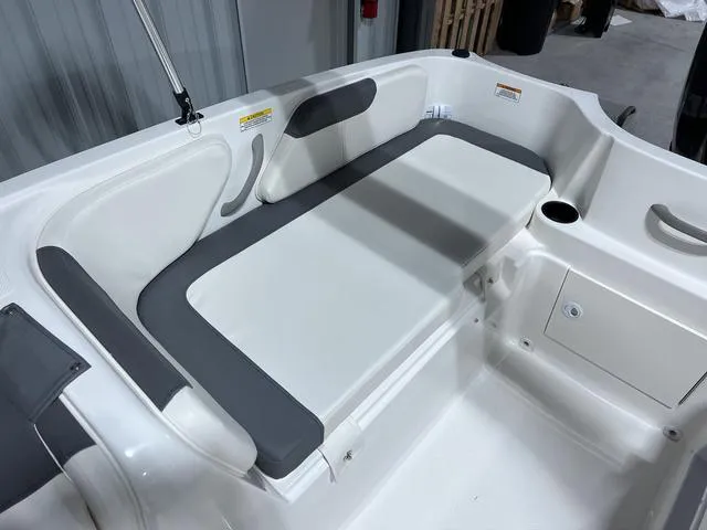 Slide: The Image of 2024 Bayliner E18 LTD boat interior seating area with white and gray cushions. - 8