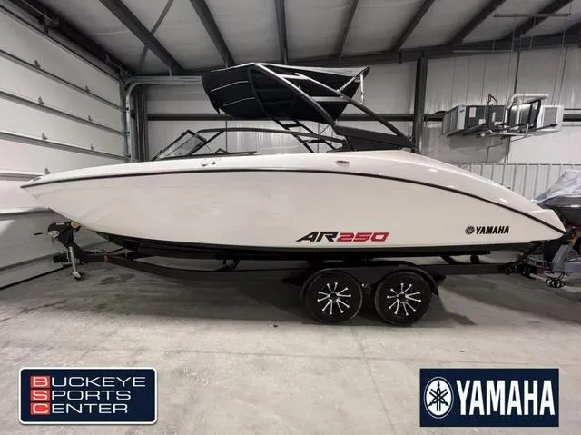 Slide: The Image of 2024 Yamaha AR250 boat in showroom, Buckeye Sports Center, white hull, black trailer. - 1