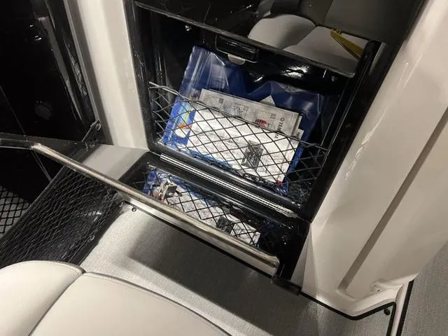 Slide: The Image of 2024 Yamaha Boats AR250 storage compartment with netting and documents. - 12