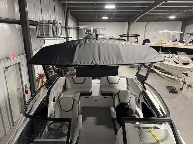 Slide: The Image of 2024 Yamaha Boats AR250 in a showroom, featuring spacious seating and a large canopy. - 28