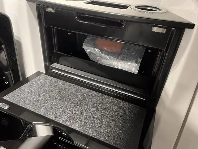 Slide: The Image of 2024 Yamaha Boats AR250 storage compartment with cup holders and black textured surface. - 8