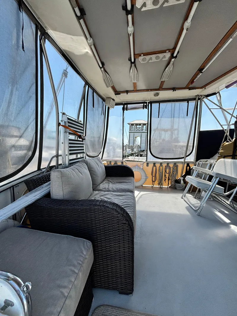 Slide: The Image of 1987 Silverton AFT CABIN interior with wicker seating and marina view. - 14