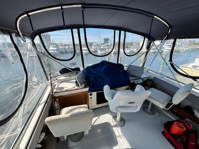 Slide: The Image of 1987 Silverton AFT CABIN boat interior with helm, chairs, and marina view. - 21