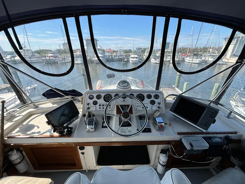 Slide: The Image of 1987 Silverton AFT CABIN helm with marina view, featuring navigation equipment and steering wheel. - 23