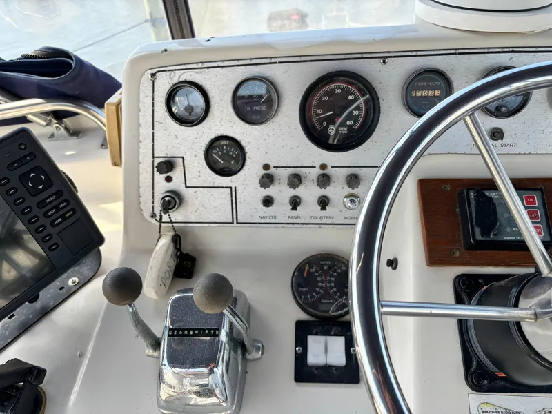 Slide: The Image of 1987 Silverton AFT CABIN boat dashboard with gauges, controls, and steering wheel. - 25