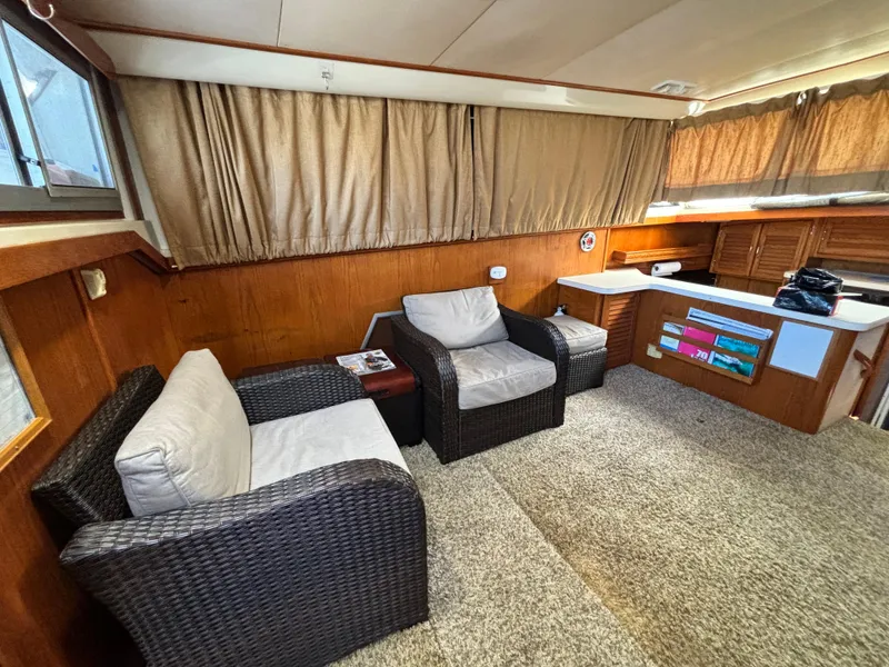 Slide: The Image of 1987 Silverton AFT CABIN interior with wicker chairs, carpet, and wood paneling. - 43