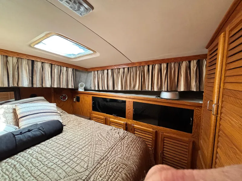 Slide: The Image of 1987 Silverton AFT CABIN interior with bed, wooden cabinets, and curtains. - 46