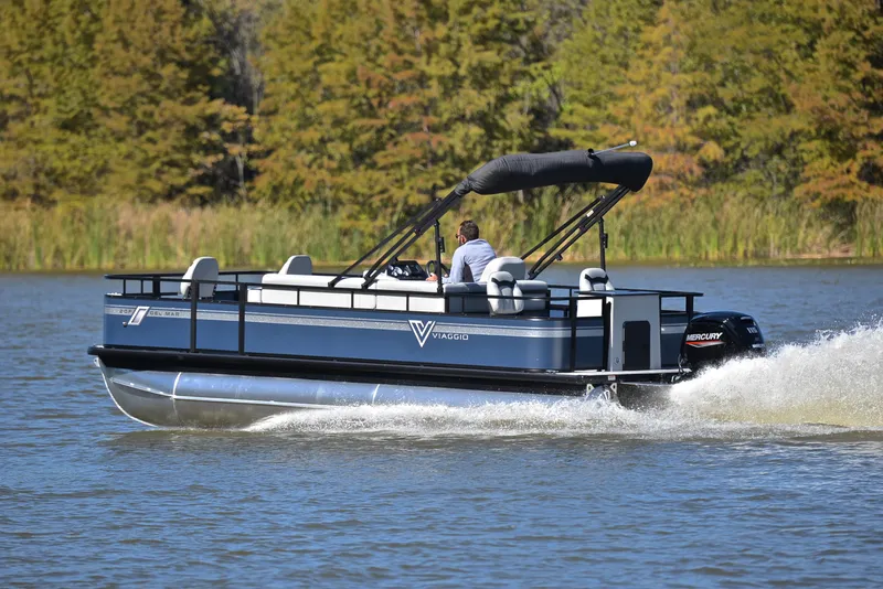 Slide: The Image of 2023 Viaggio DM20F pontoon boat cruising on a lake with trees in the background. - 4
