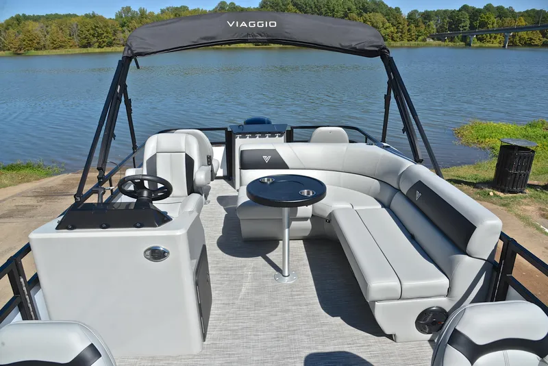 Slide: The Image of 2023 Viaggio DM18F pontoon boat with spacious seating and a table, docked by a serene lake. - 23