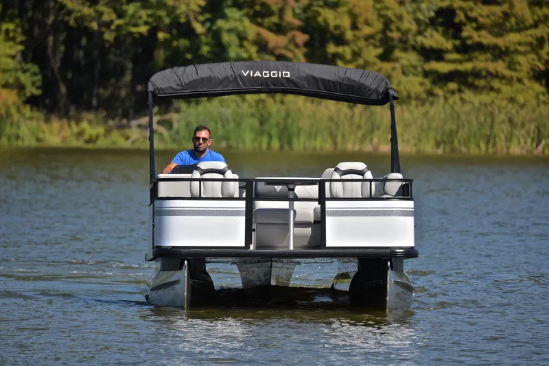 Slide: The Image of 2023 Viaggio DM18F pontoon boat on a lake with a man at the helm. - 9