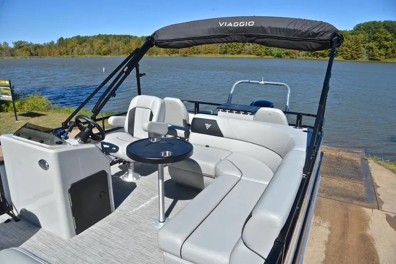 Slide: The Image of Viaggio DM18F 2023 pontoon boat with gray seating, black canopy, and lake backdrop. - 21