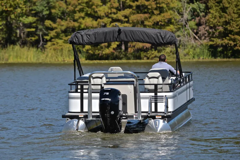 Slide: The Image of 2023 Viaggio DM18F pontoon boat cruising on a lake with a person at the helm. - 7