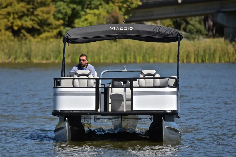 Slide: The Image of 2023 Viaggio DM18F pontoon boat on a lake with a person driving. - 8