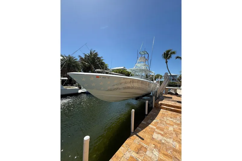 Slide: The Image of 2023 Contender 44 ST boat docked by a sunny waterfront with palm trees. - 2
