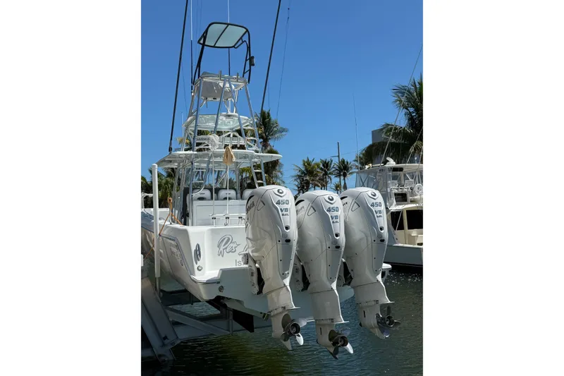 Slide: The Image of 2023 Contender 44 ST boat with triple 450 V8 engines docked in sunny marina. - 3