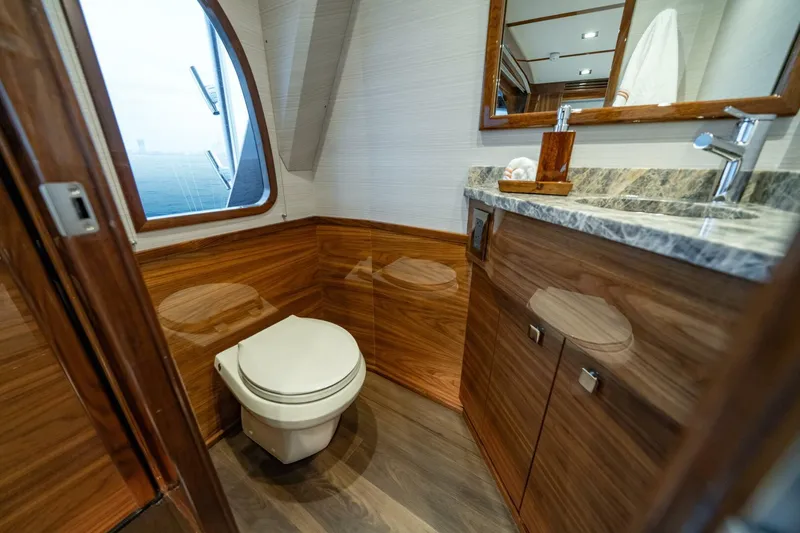 Slide: The Image of Luxurious bathroom in 2025 Viking 82 Convertible yacht with wood accents and marble countertop. - 23