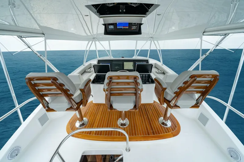 Slide: The Image of 2025 Viking 82 Convertible yacht helm with ocean view, featuring three wooden chairs. - 5