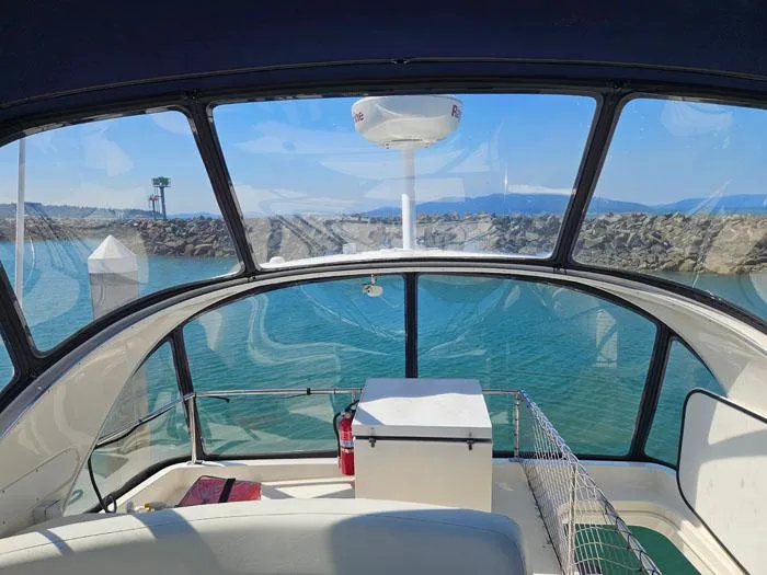 Slide: The Image of View from 2007 Meridian 411 Sedan boat cockpit overlooking calm blue waters and rocky shoreline. - 25