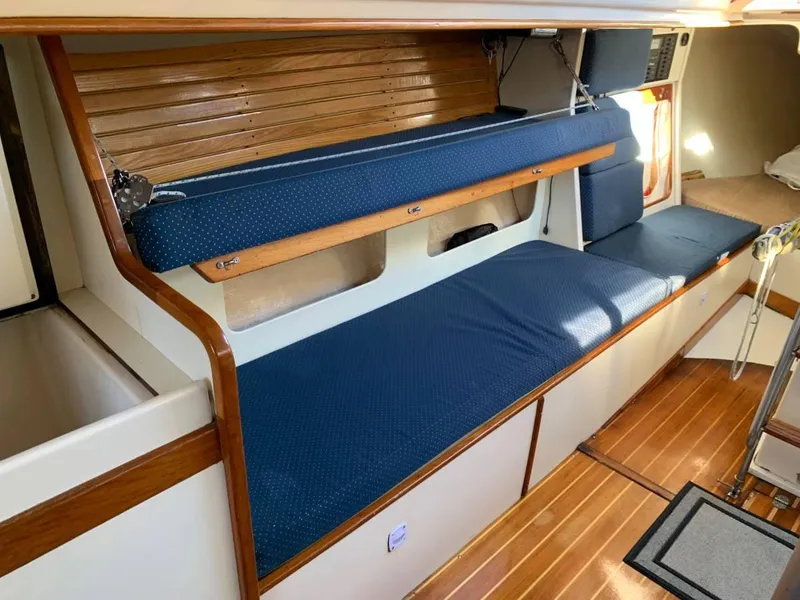 Slide: The Image of Interior of a 1991 Tripp 36 sailboat with blue cushioned seating and wooden accents. - 13
