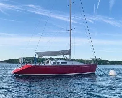 Slide: The Image of Red 1991 Tripp 36 sailboat anchored on calm water under a clear blue sky. - 2