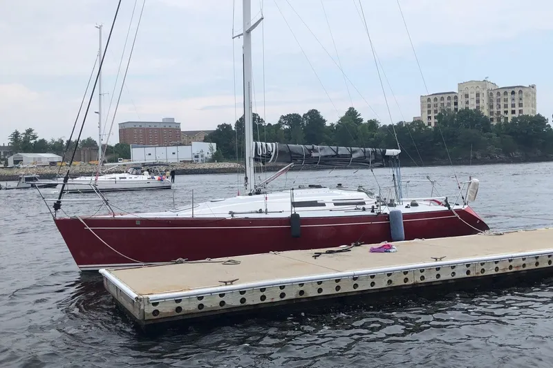 Slide: The Image of Red Tripp 36 sailboat docked on calm water, 1991 model, with buildings in the background. - 3