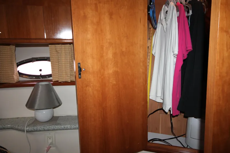 Slide: The Image of Wooden closet interior of 2001 Carver 466 Motor Yacht with hanging clothes and a lamp. - 26