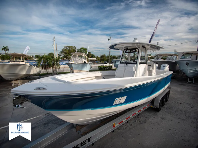 Slide: The Image of 2024 Regulator 31 boat on trailer at marina, blue hull, center console. - 2