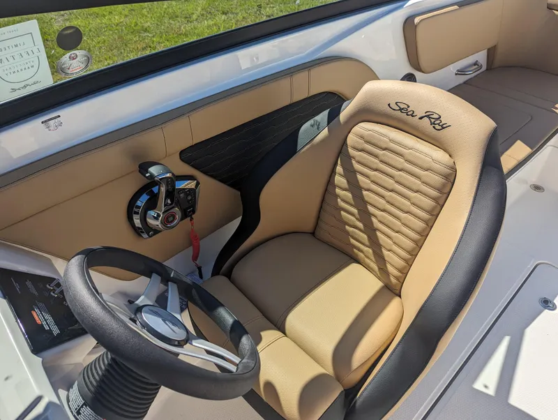 Slide: The Image of 2024 Sea Ray SPX 230 boat interior with tan and black captain's seat and steering wheel. - 15