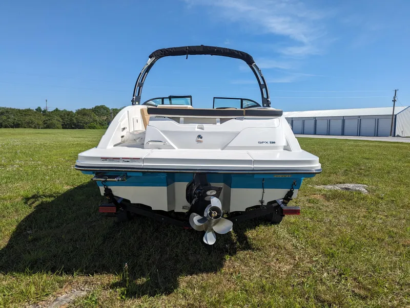 Slide: The Image of 2024 Sea Ray SPX 230 boat, rear view on grass, blue sky background. - 2