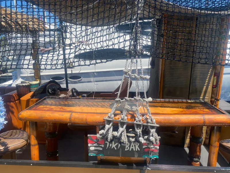 Slide: The Image of Custom Tiki Bahama Mama 1.0 boat bar, 2024 model, with bamboo decor and nautical netting. - 2