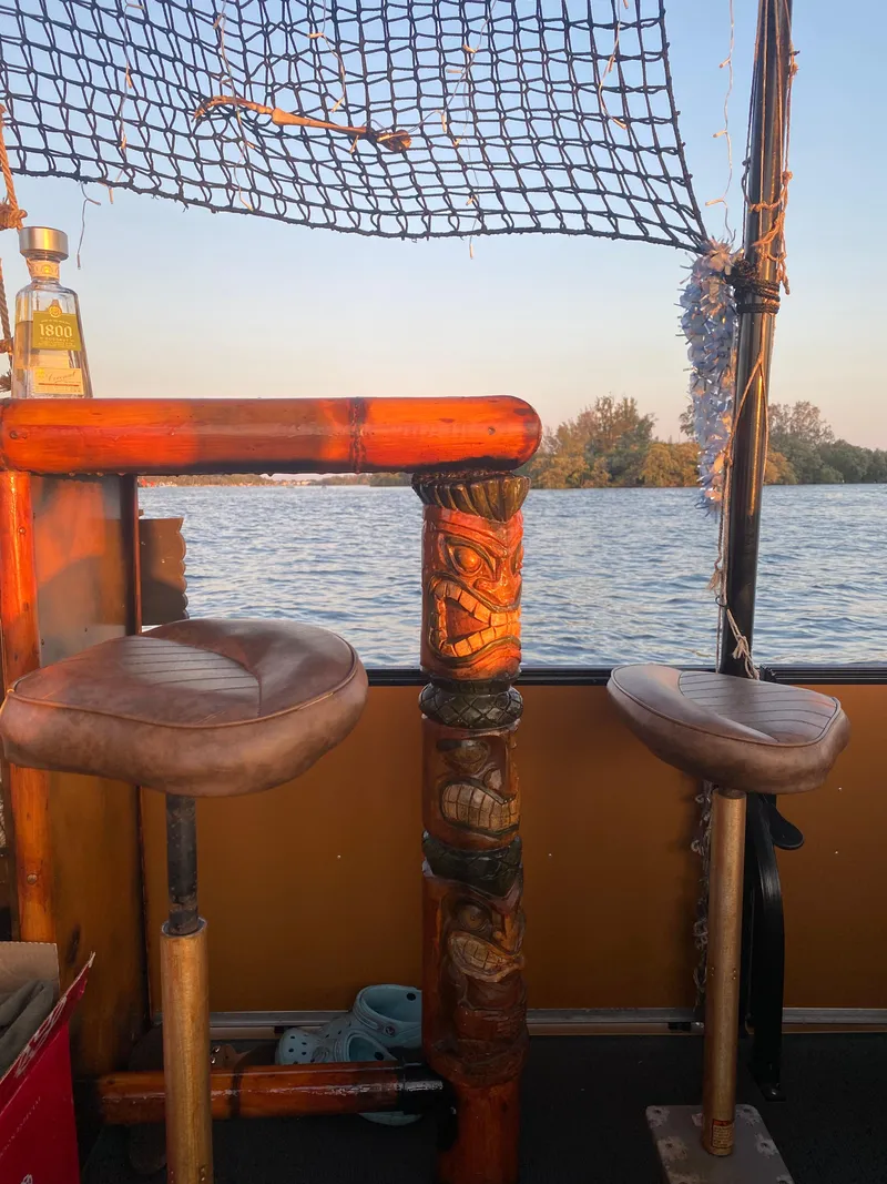 Slide: The Image of Tiki-themed boat bar with stools overlooking serene water, Custom Tiki Bahama Mama 1.0, 2024. - 3