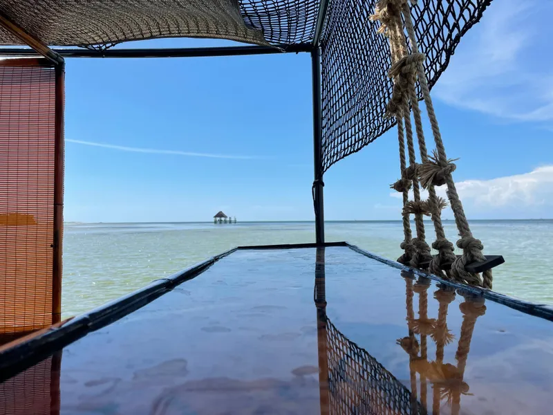 Slide: The Image of Custom Tiki Bahama Mama 1.0 boat, 2024 model, on serene tropical waters with distant hut. - 7