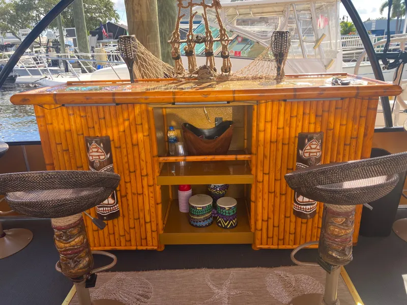 Slide: The Image of Tiki Bahama Mama 2.0 2024 custom bamboo bar with stools on a boat dock. - 2