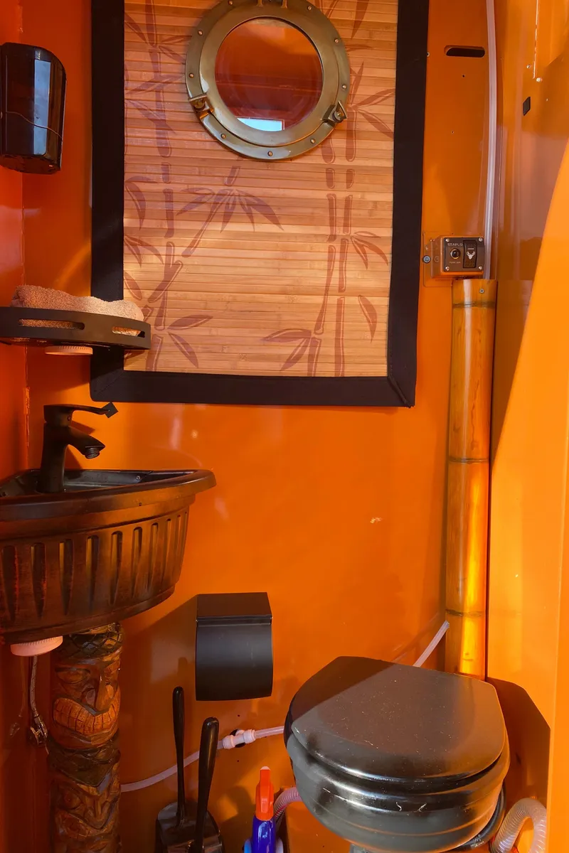 Slide: The Image of Custom Tiki Bahama Mama 2.0 2024 bathroom with bamboo decor and porthole window. - 5