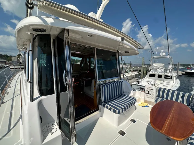 Slide: The Image of 2012 Sabre 48 Salon Express yacht with open deck and striped seating at marina. - 4