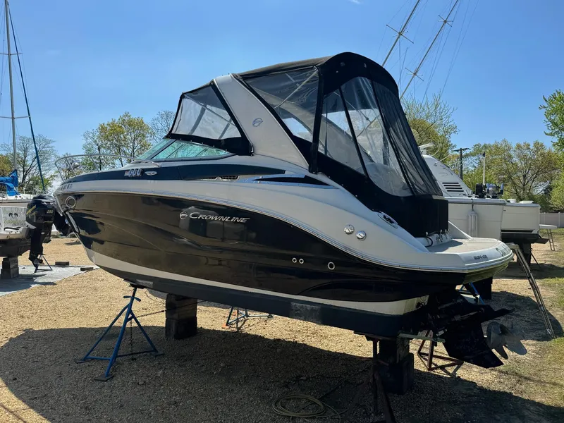 Slide: The Image of 2020 Crownline 264CR boat on stands, black and white exterior, covered cockpit. - 1